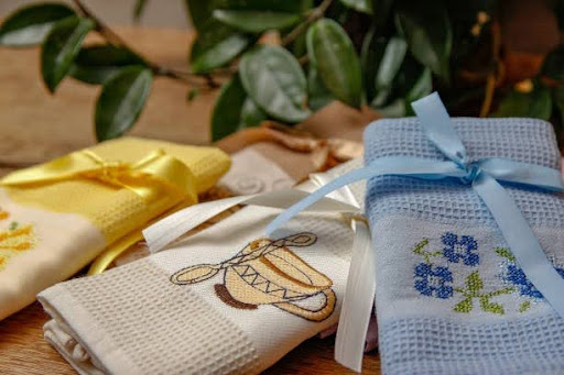 Personalized kitchen towels with custom embroidered patterns tied with ribbons.
