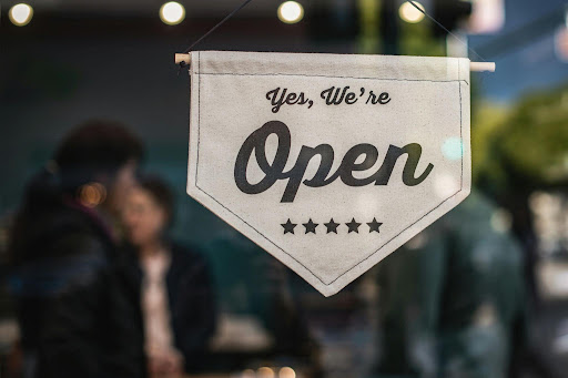 Beige fabric pennant sign featuring the " Yes We're Open message and stars.