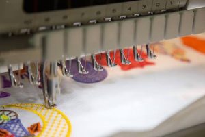 Embroidery machine stitching a detailed logo onto fabric.